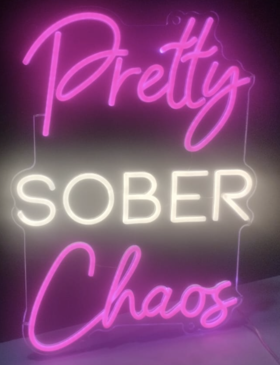 The Pretty Sober Chaos neon sign — Pretty in pink script, SOBER in white block letters, Chaos in pink script.
